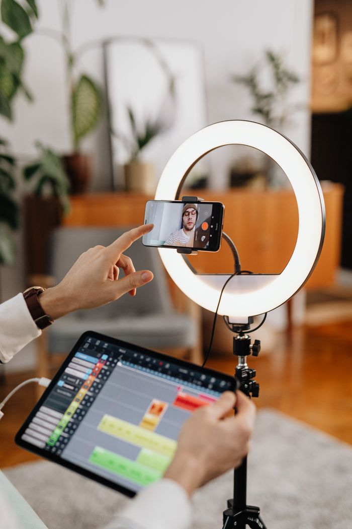 project-01-c A content creator is filming indoors with a smartphone and ring light setup for vlogging.